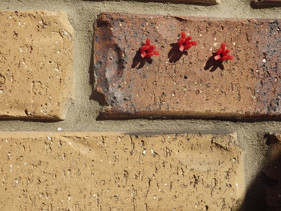 3 Scorpion Wall Plugs shown in first position when installed in drilled holes in solid brick wall before being pushed deeper into hole